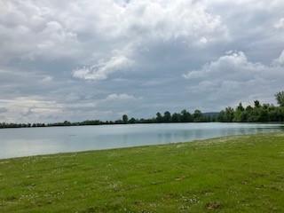 Badeweiher mit grüner Liegewiese im Vordergrund