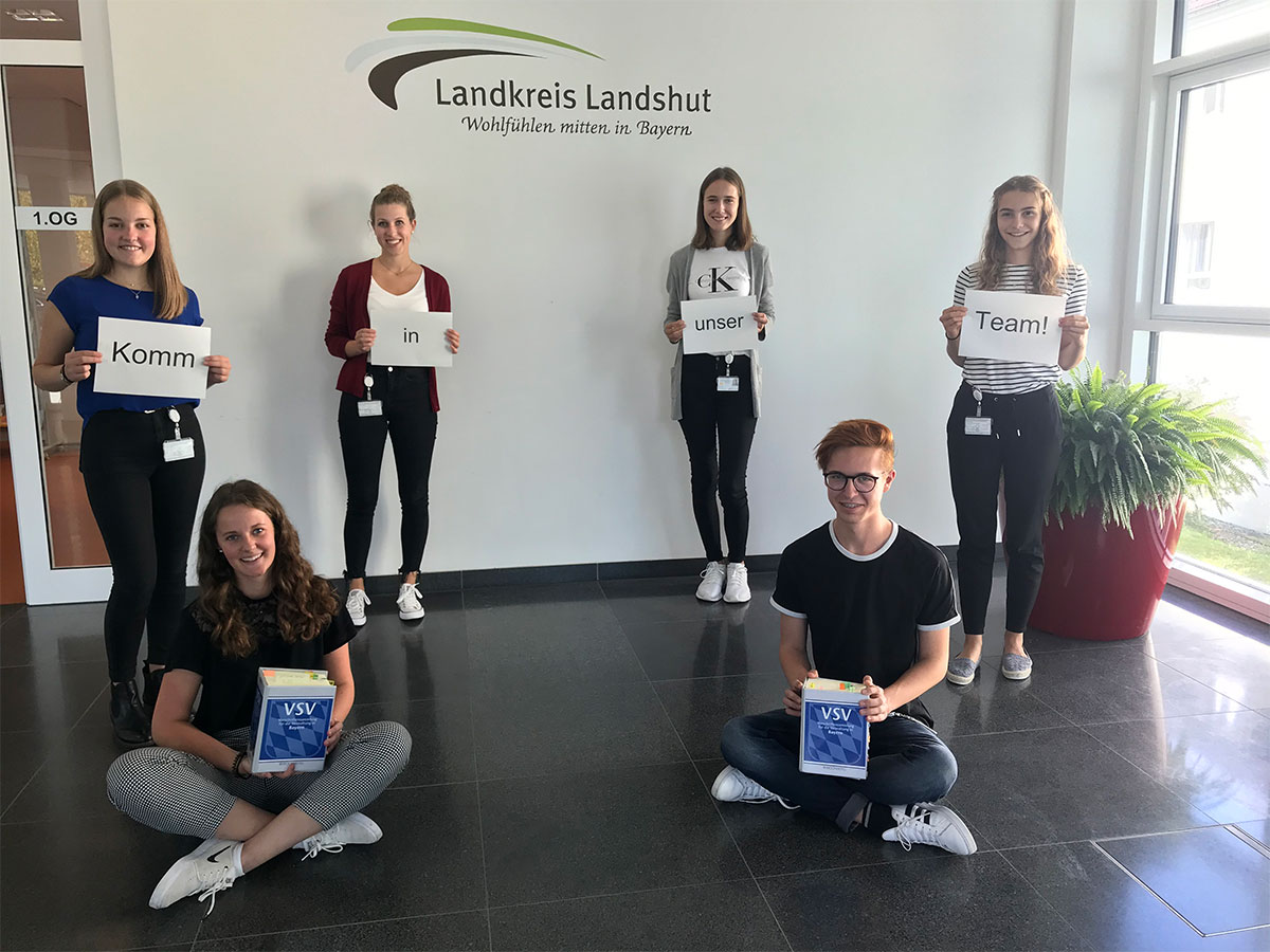bewerbungsaufforderung-landkreis-landshut Gruppe junger Erwachsender hält Papierschilder in die Höhe