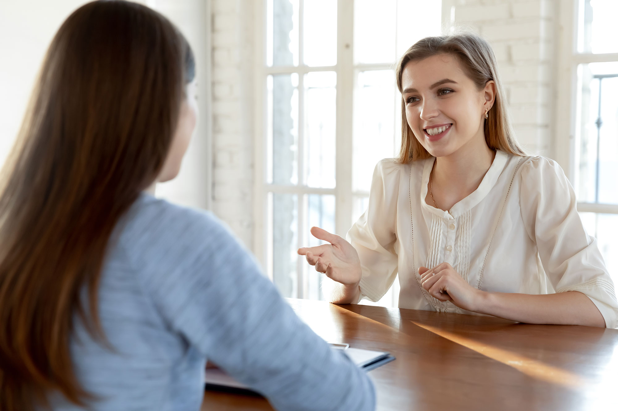 Zwei Frauen sitzen sich an einem Tisch gegenüber