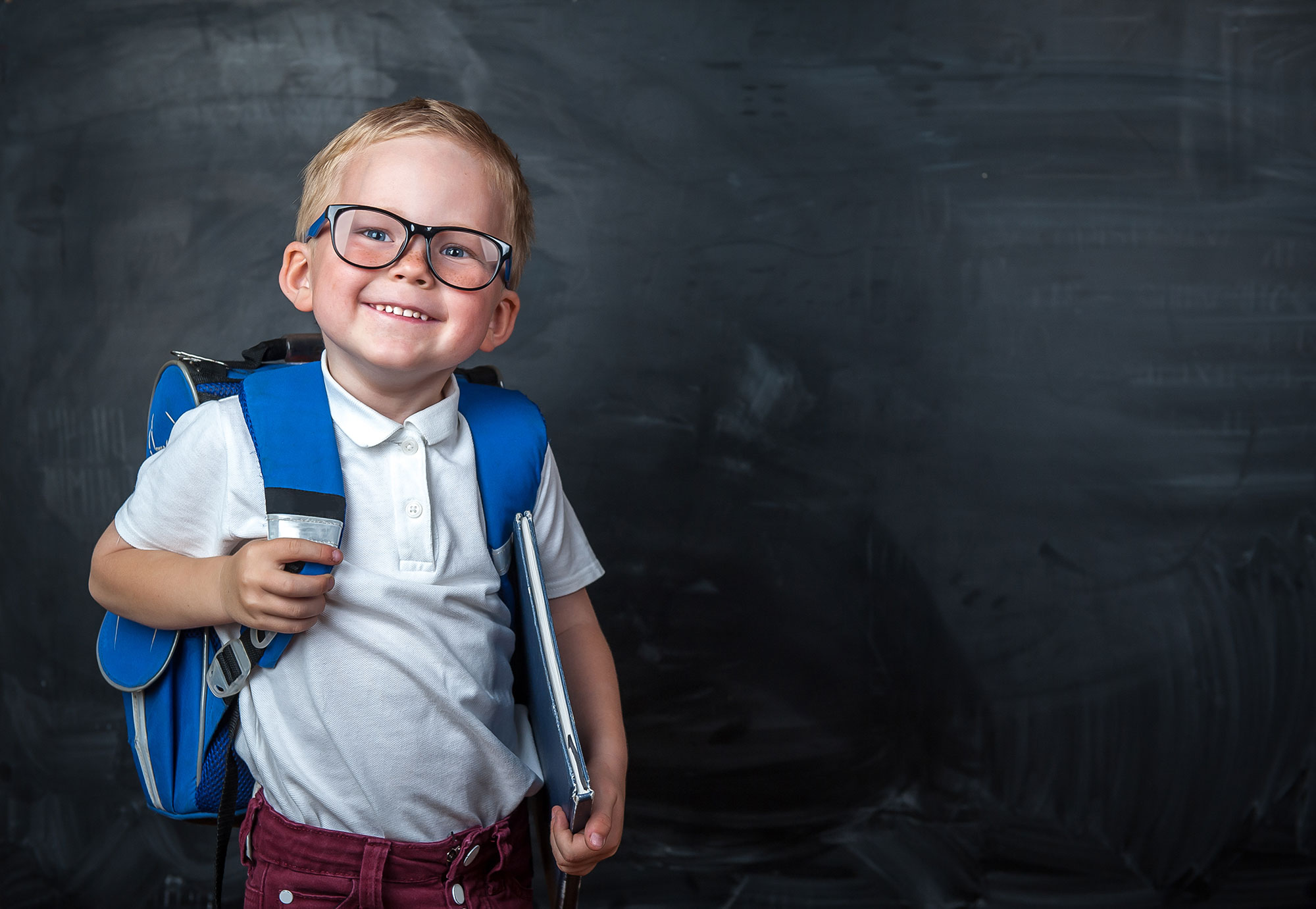 Junge mit Brille vor einer Schultafel