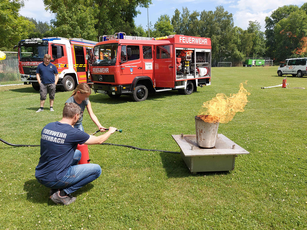 Person auf Rasen, Feuerwehrauto, Feuerstelle