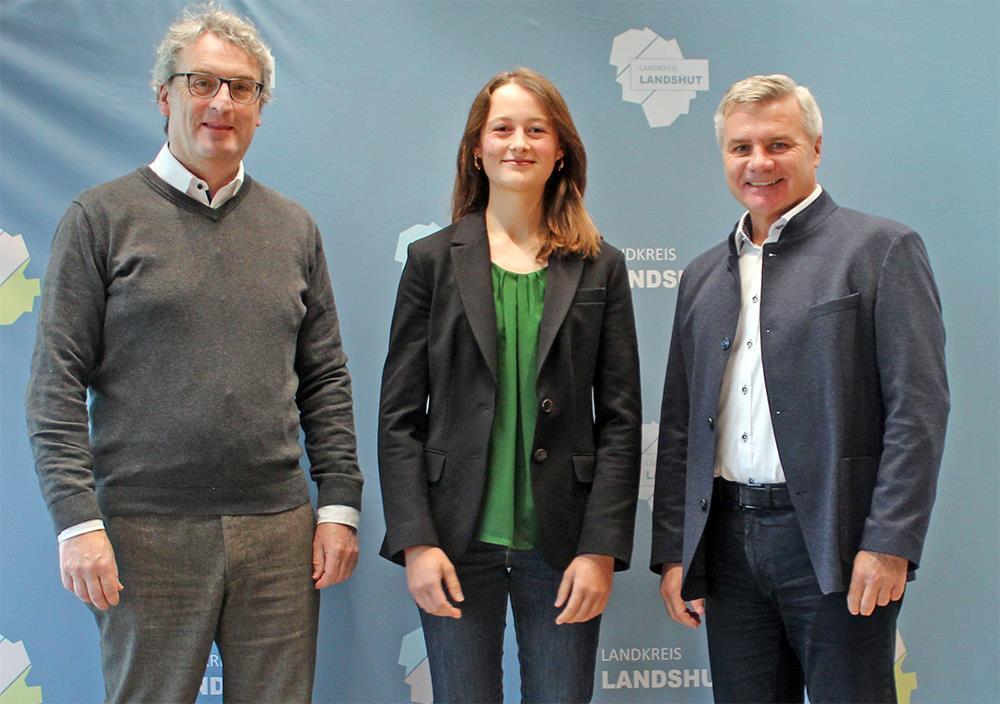 Junge steht zwischen zwei Männern vor einer Fotowand