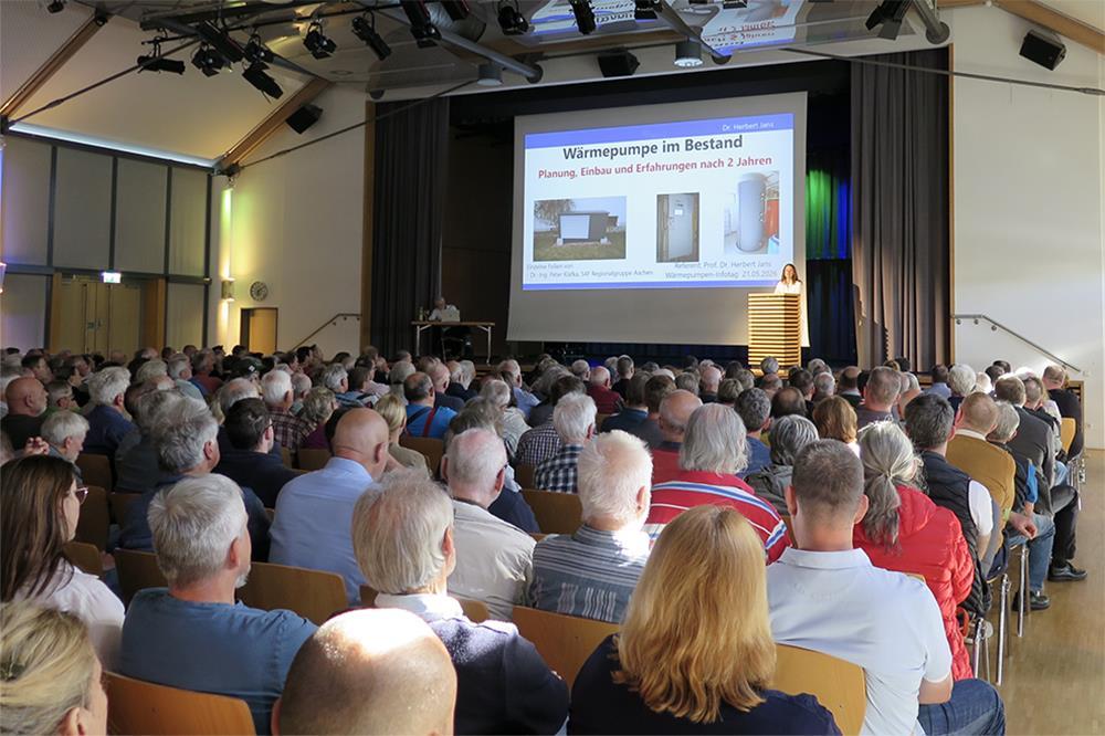 Mehrere Menschen verfolgen in einem Saal einen Vortrag